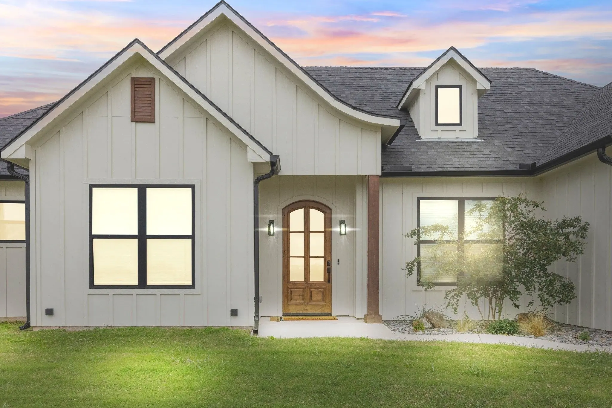 An O'Brien home at dusk with an arched timber front door and mature planting.