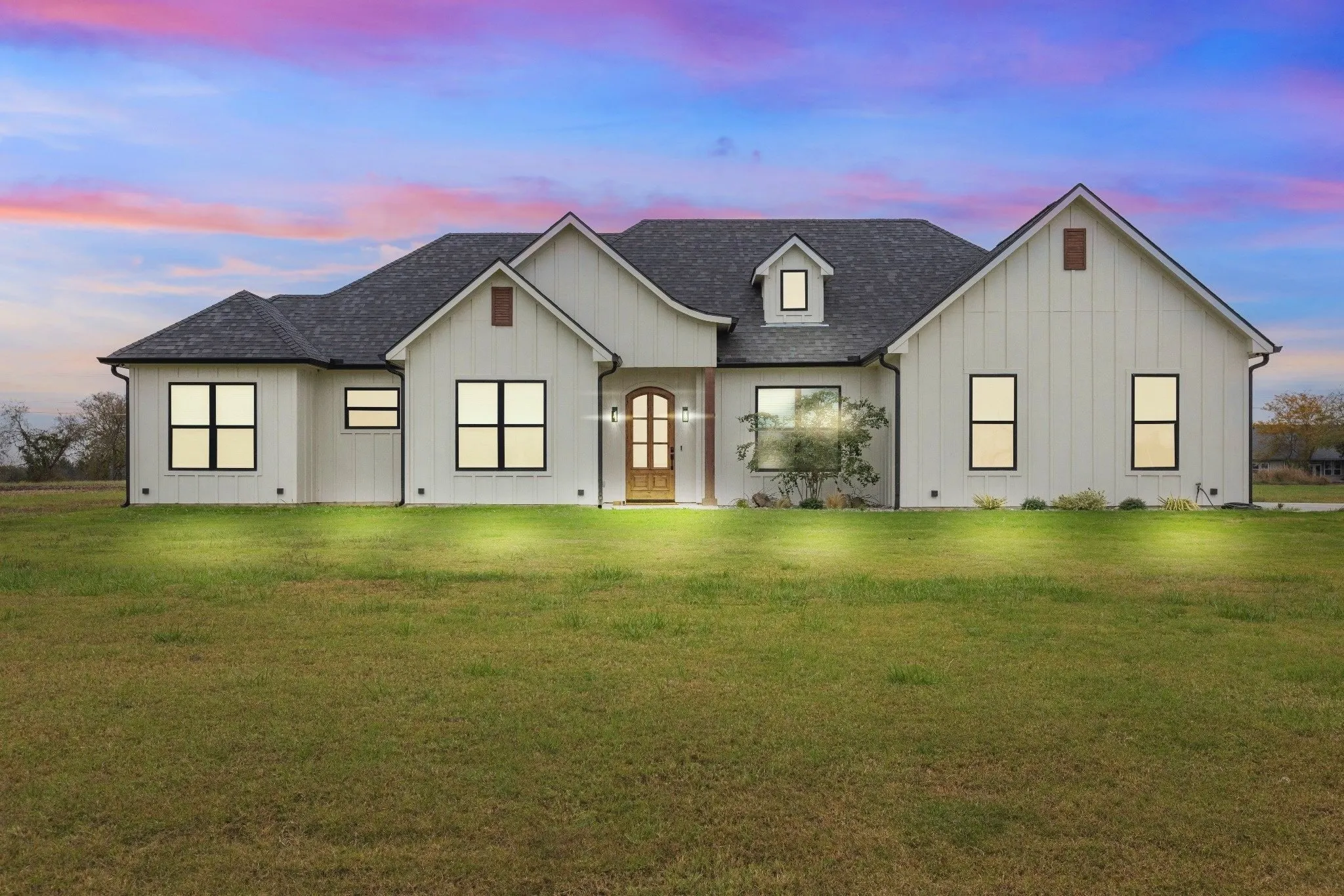 A custom modern farmhouse at twilight on open land in Grayson County, Texas