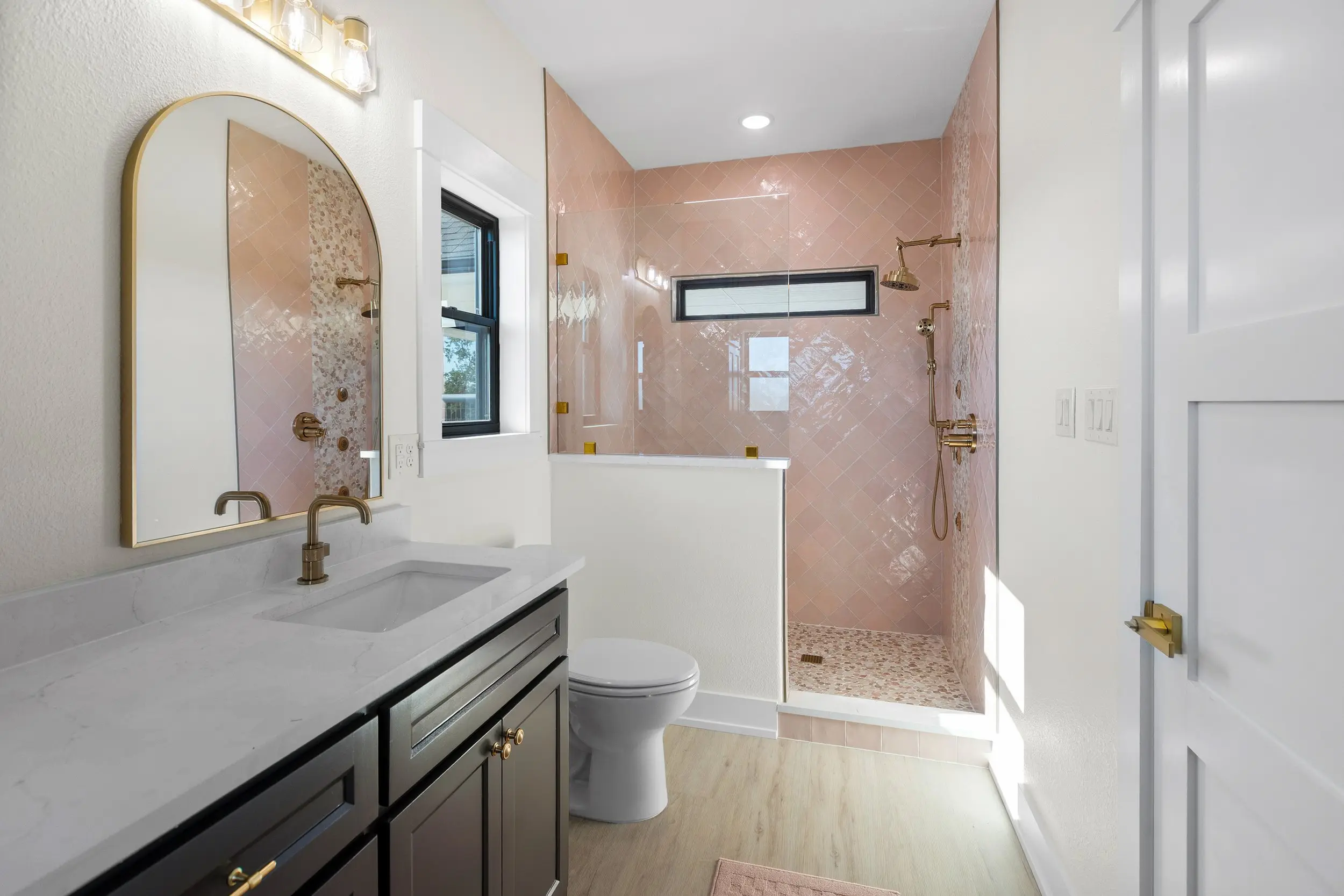 Guest bathroom with an arched mirror and pink tile, The Lugo House, a custom home in Sherman, Texas