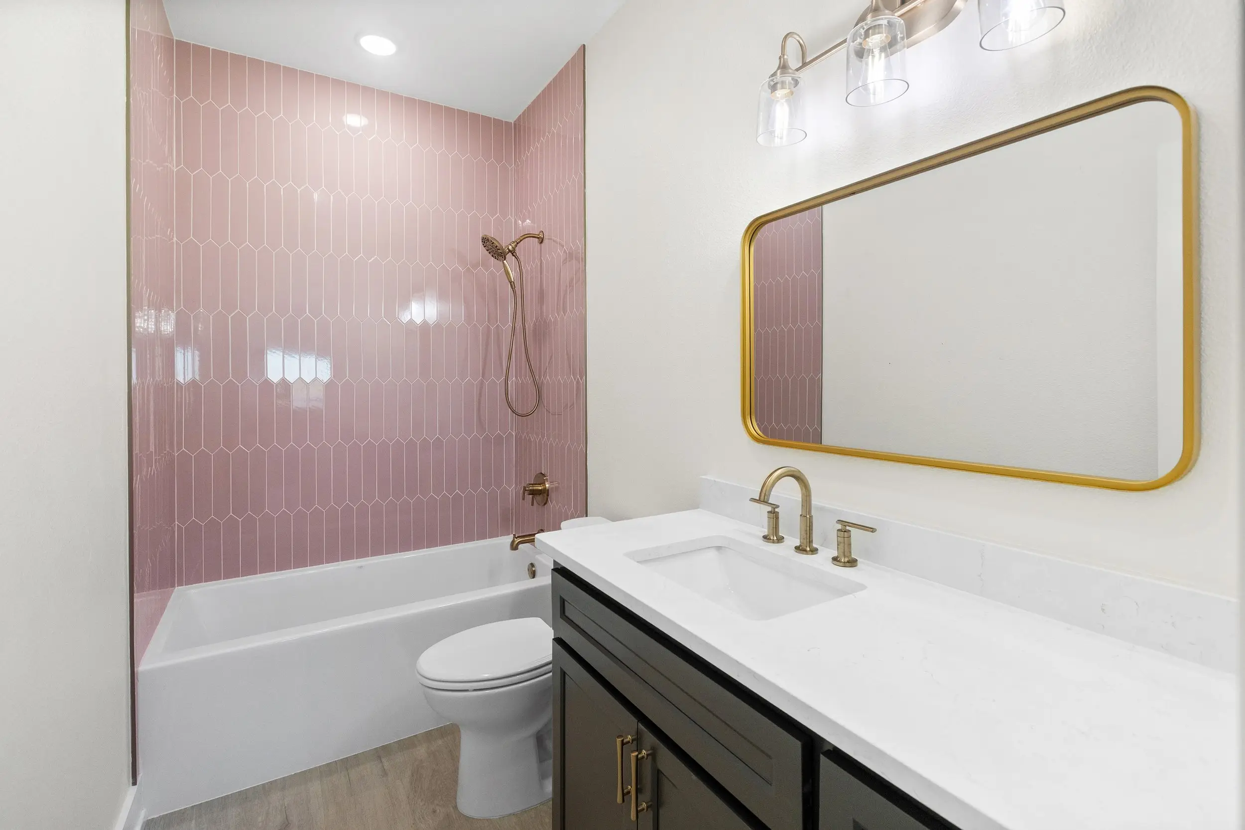 Guest bathroom with a pink tiled shower and gold fixtures, The Lugo House, a custom home in Sherman, Texas