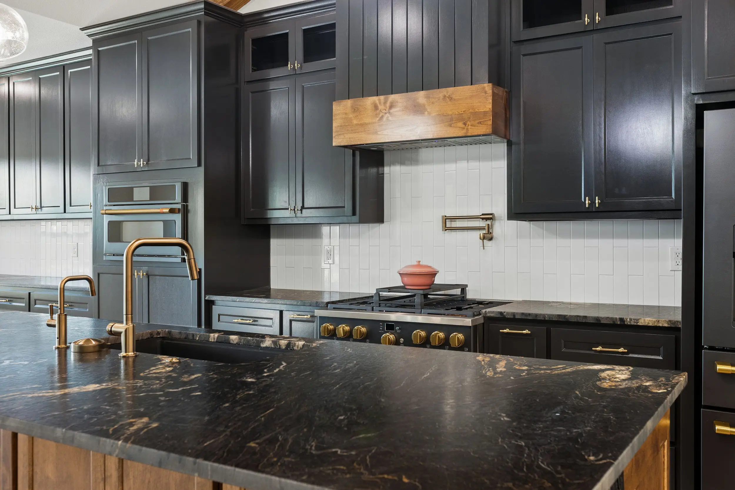 Kitchen with a gas range under a wood vent hood, The Lugo House, a custom home in Sherman, Texas