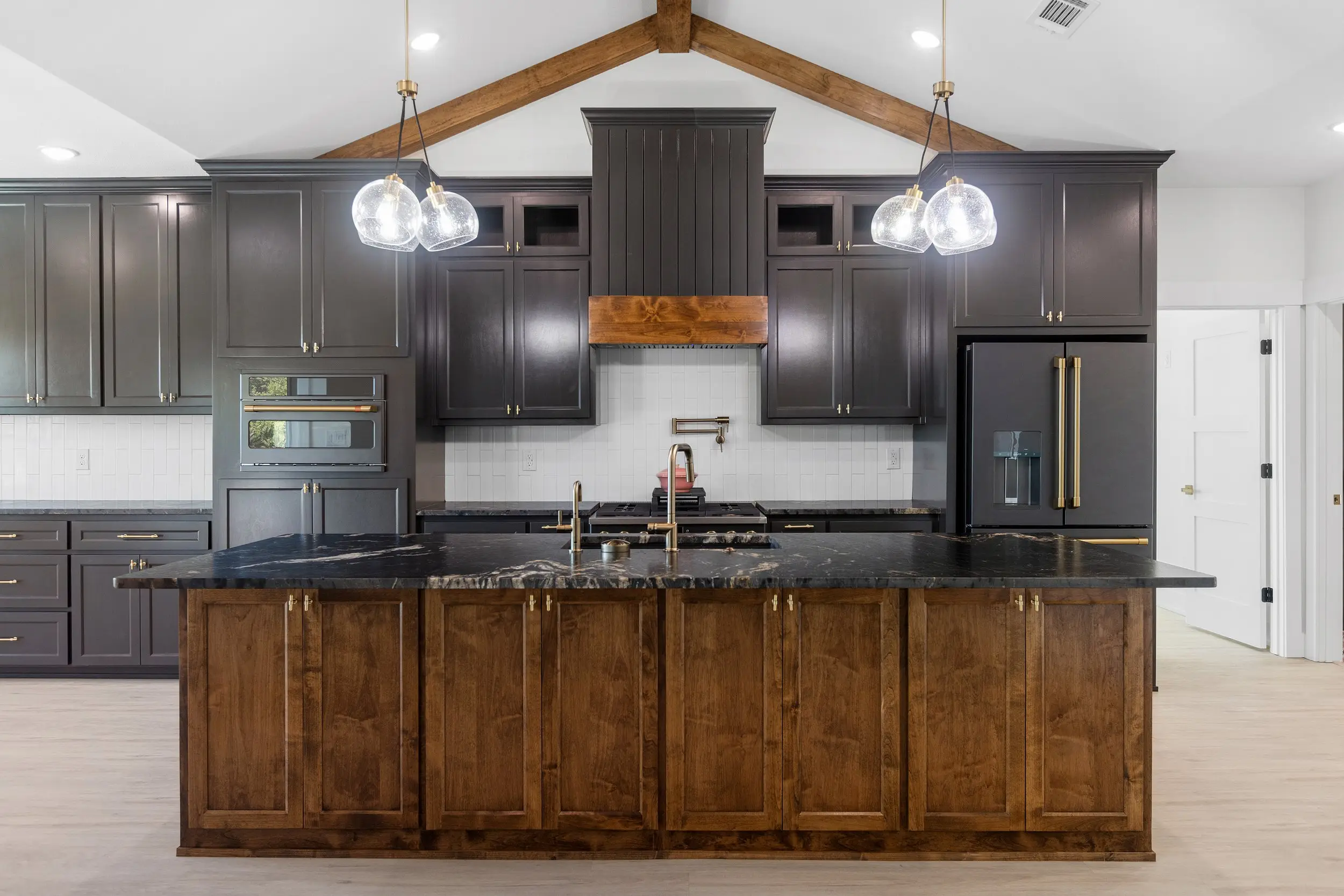 Kitchen island under pendant lights and beams, The Lugo House, a custom home in Sherman, Texas