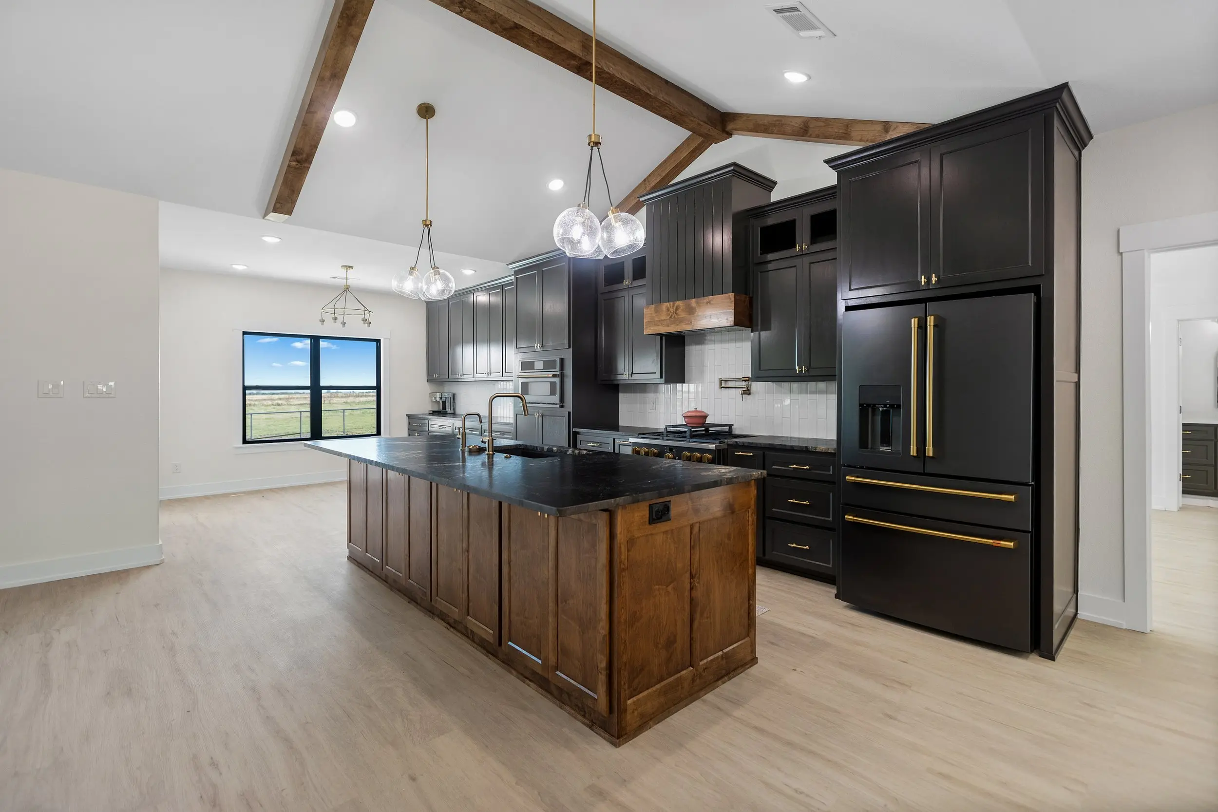 Kitchen open to the living room under exposed beams, The Lugo House, a custom home in Sherman, Texas
