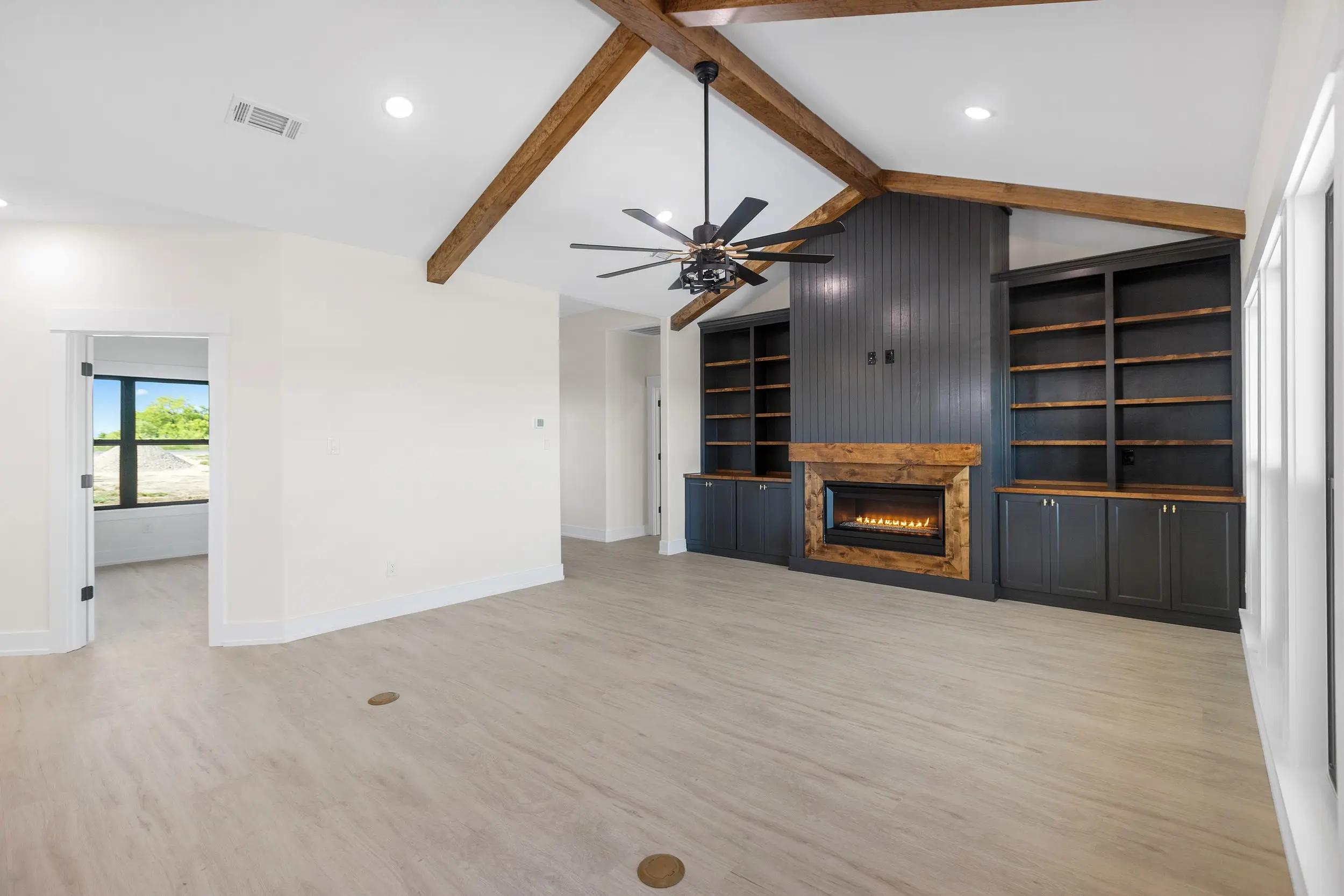 Living room with a fireplace under exposed beams, The Lugo House, a custom home in Sherman, Texas