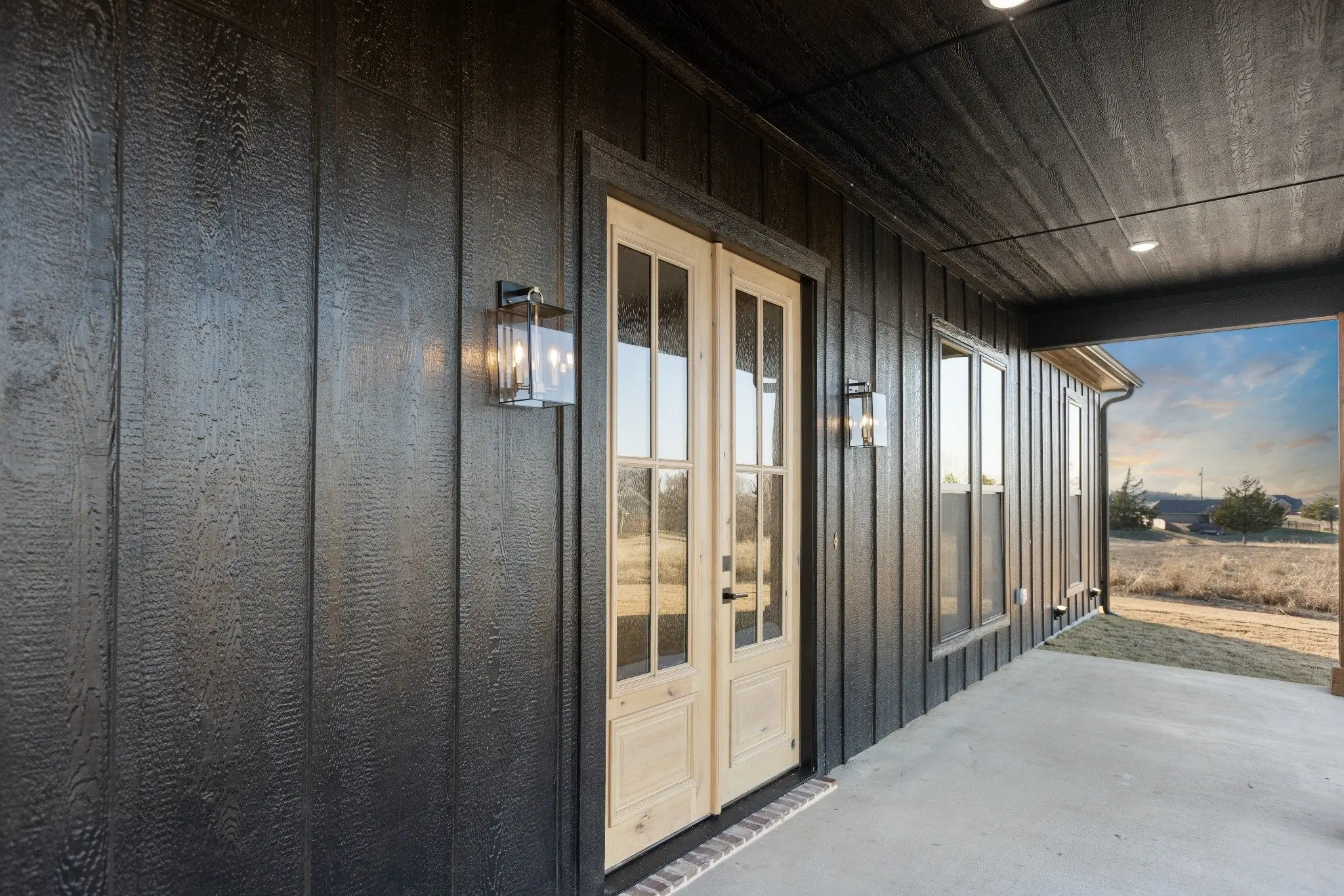 Covered porch with French doors and dark siding, The Wester House, a custom home in Sherman, Texas