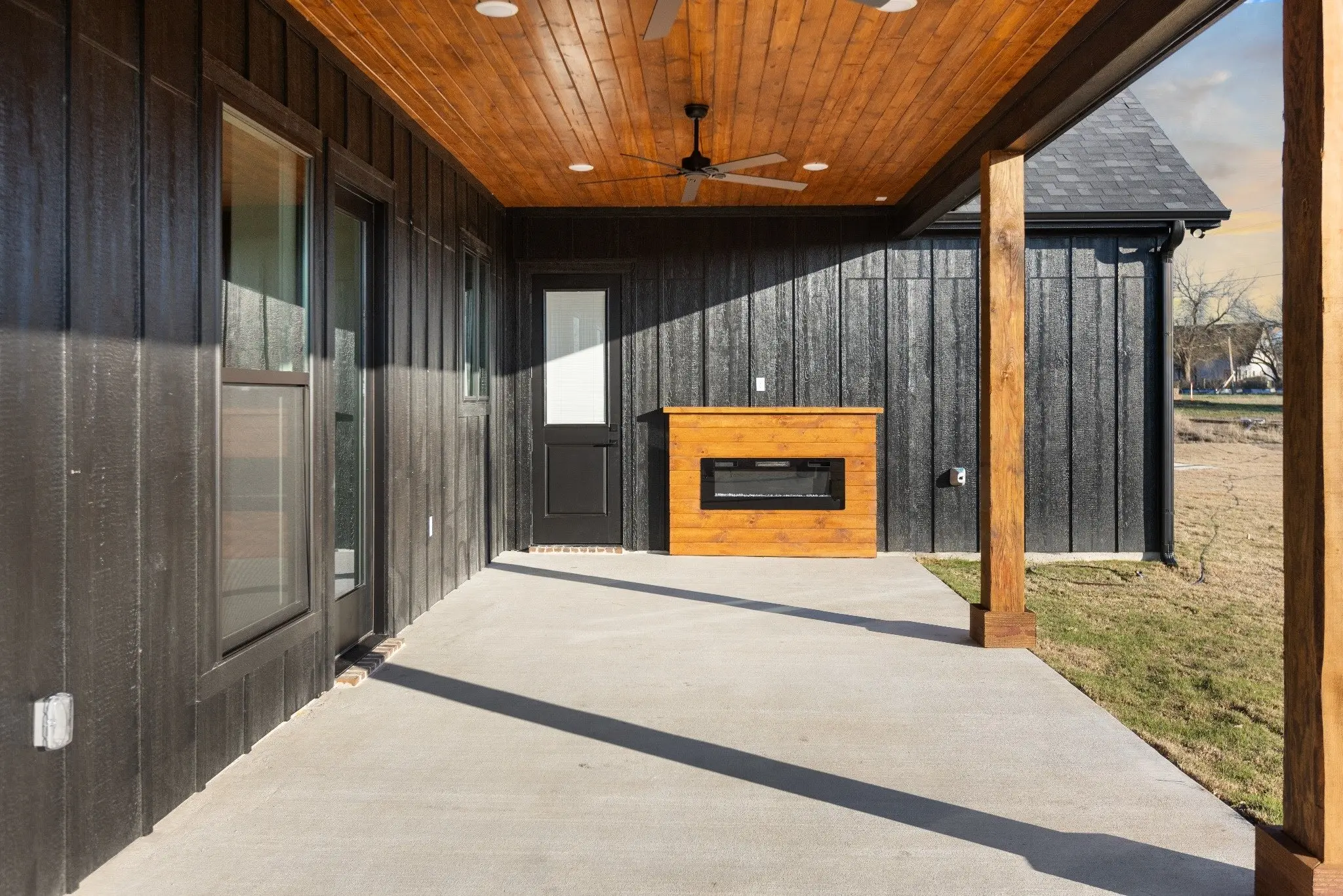 Covered porch with an outdoor fireplace and cedar ceiling, The Wester House, a custom home in Sherman, Texas