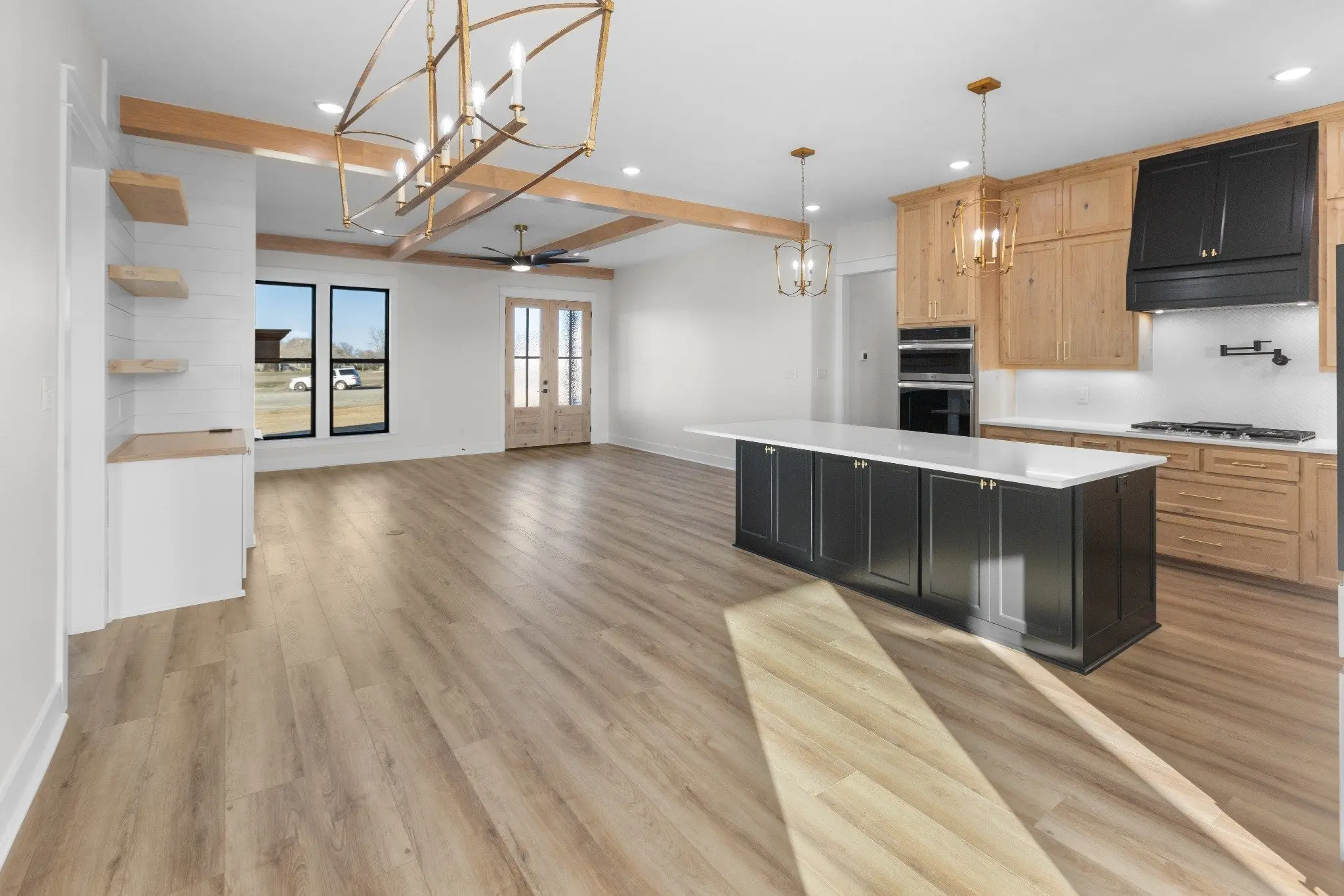 Kitchen and great room with a dark island under a beamed ceiling, The Wester House, a custom home in Sherman, Texas